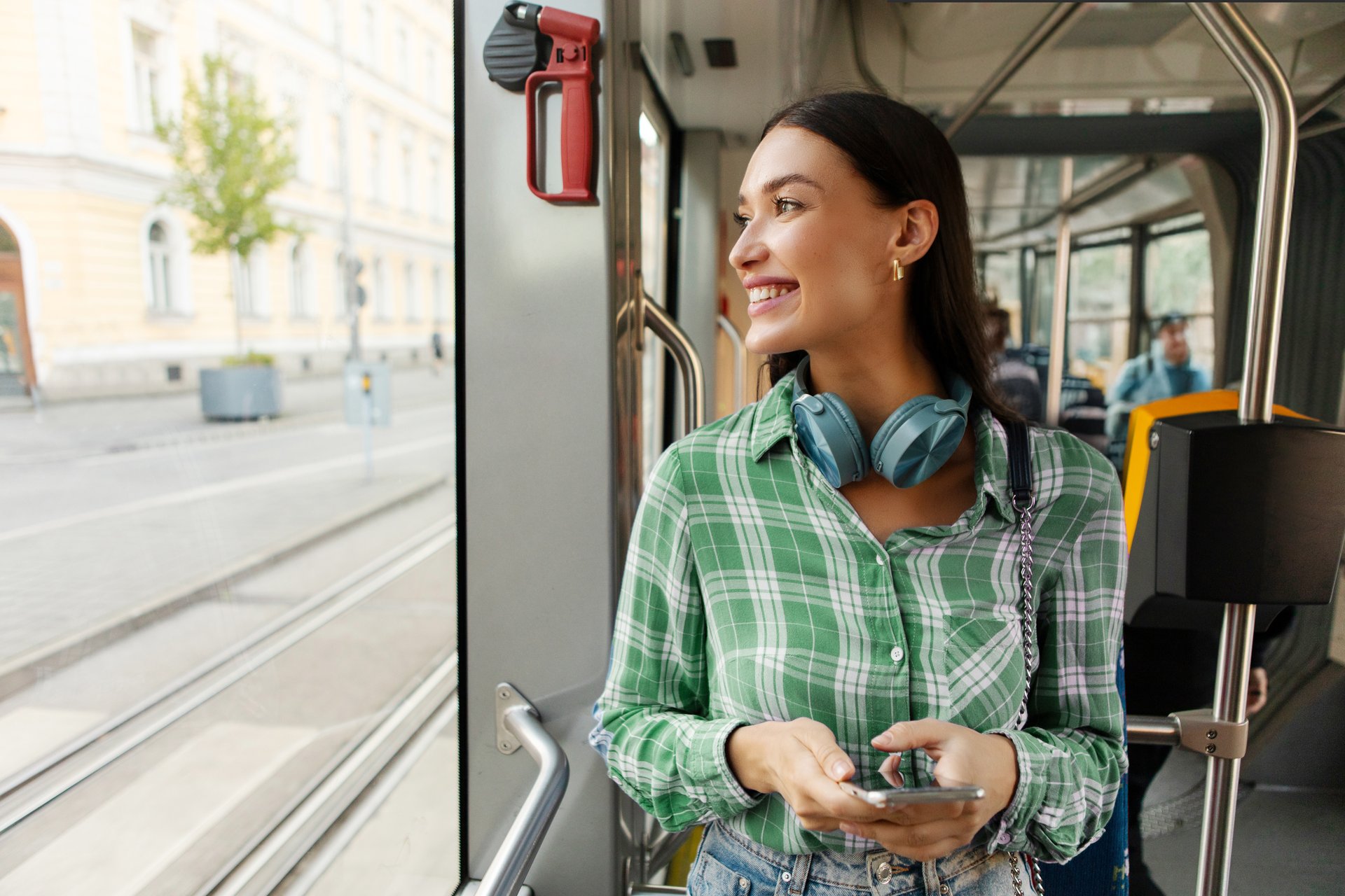 Uśmiechnięta studentka ze słuchawkami jedzie tramwajem
