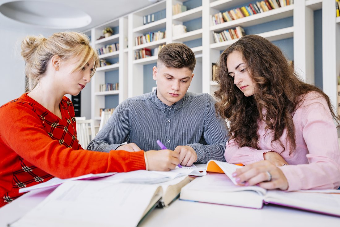 Trójka studentów uczy się razem w bibliotece