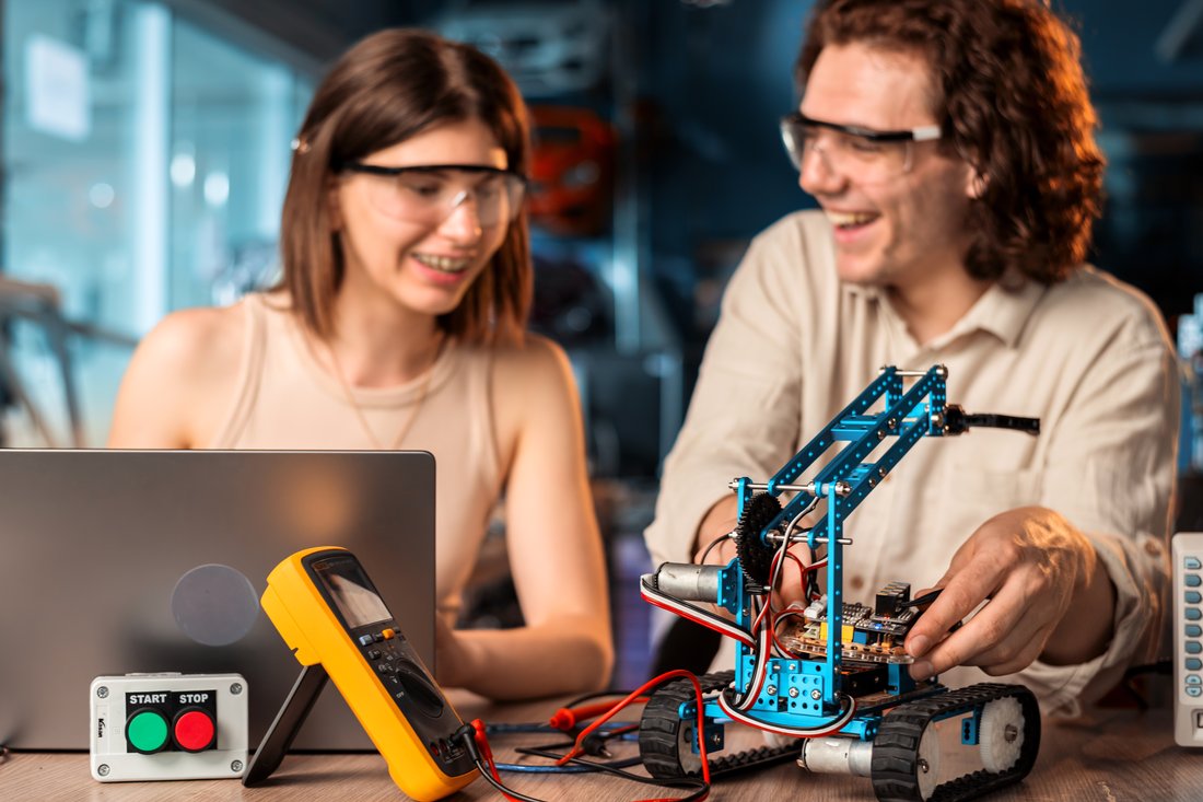 Studentka i student w okularach ochronnych budują robota w laboratorium